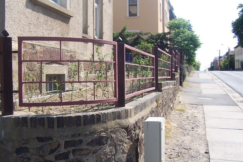 Natursteinmauer mit Eisenzaun